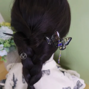 Traditional Chinese butterfly hair stick with purple blue beaded tassel shown in a braided bun hairstyle with floral styling