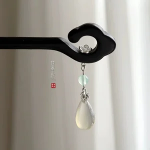 Front view of traditional Chinese cloud hair stick in matte black wood with floral detail and green dangling pendant