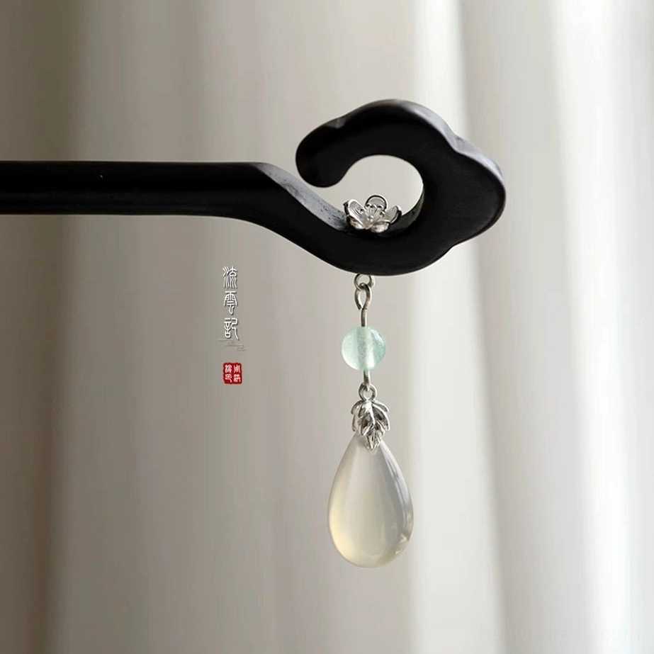 Front view of traditional Chinese cloud hair stick in matte black wood with floral detail and green dangling pendant