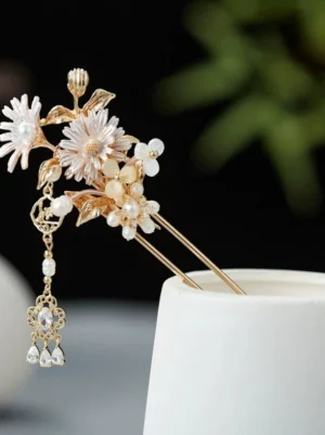 Front view of traditional Chinese daisy hair stick with pearl decorations, gold metal leaves, and dangling crystal tassel on a ceramic display