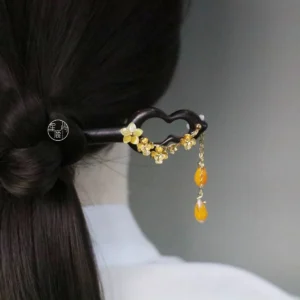 Traditional Chinese dark wooden hair stick with carved openwork ornament golden flower embellishments crystal details and double amber tassels worn with a low Hanfu hairstyle
