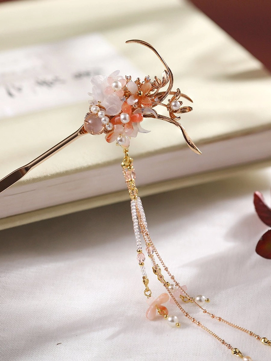 Traditional Chinese floral hair stick shown on light-colored books with pearl accents, pink white flowers, layered chains, and delicate flower tassel pendants