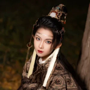 Front close-up of a woman wearing an intricate traditional Chinese hair crown with forehead chain long white tassels dangling pendants and dark Hanfu styling