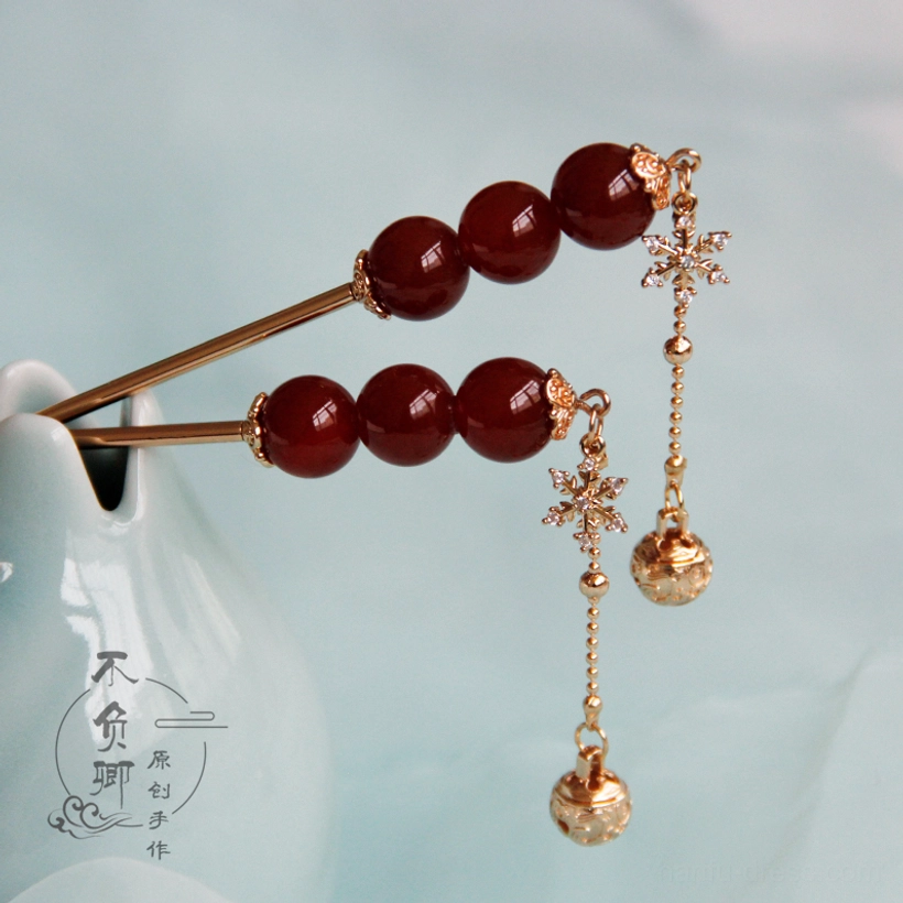 Traditional Chinese hair pin and hair stick designs with red bead ornaments snowflake charms and bell tassels displayed beside a ceramic vase
