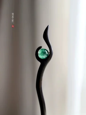 Traditional Chinese hair stick with sleek black wooden shaft and round emerald green jade decoration in a swallow-tail inspired silhouette