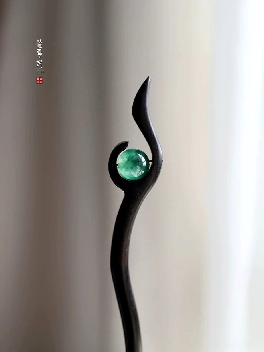 Traditional Chinese hair stick with sleek black wooden shaft and round emerald green jade decoration in a swallow-tail inspired silhouette