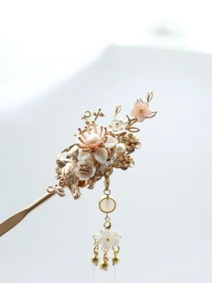 Front close-up of traditional Chinese hair stick featuring pearl-style center, gold floral carving, pink blossoms, beads, and hanging pendant