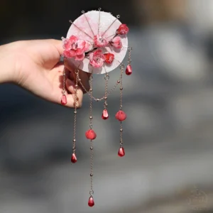 Front view of traditional Chinese hair stick accessory with pink red plum blossoms staggered tassel chains and red pendant details