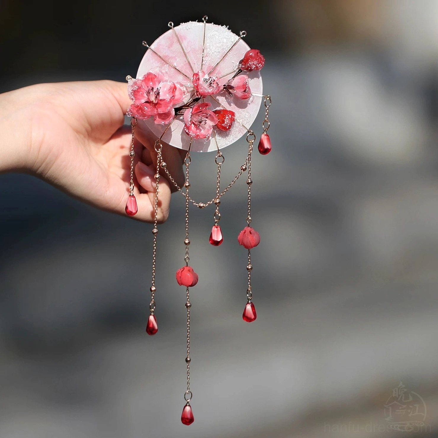 Front view of traditional Chinese hair stick accessory with pink red plum blossoms staggered tassel chains and red pendant details