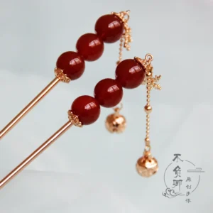 Traditional Chinese hair stick featuring red tanghulu-style beads gold metal fittings snowflake decoration and elegant bell tassel close-up
