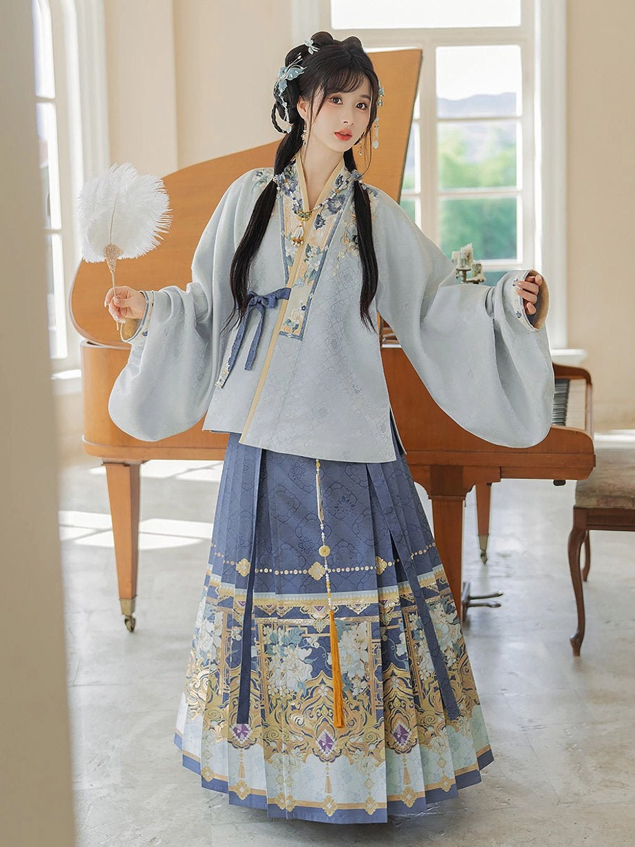 Traditional Chinese Hanfu full outfit with pale blue cross-collar top, pleated embroidered mamian skirt, blue sash, and white feather fan