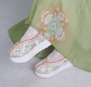 Pair of traditional Chinese Hanfu shoes for women featuring pink and green flower embroidery, pink edging, decorative toe ornaments, and white platform rubber soles