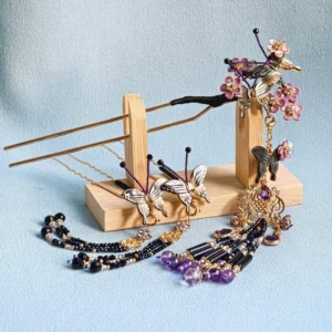 Traditional Chinese Hanfu hair accessory display featuring a butterfly floral hair stick, purple tassels, golden ornaments, and jewel-toned decorative details