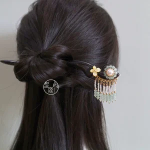 Chinese Hanfu hair stick with floral decoration, faux pearl, and light green tassel displayed in a twisted low bun hairstyle from the back