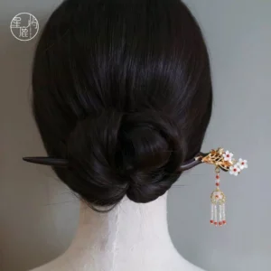 Traditional Chinese Hanfu hair stick with gold flower decoration and red white beaded tassel secured in a low chignon hairstyle