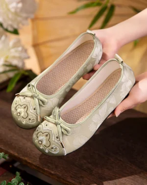 Traditional Chinese Hanfu shoes held by female hands showing the full embroidered cloth shoe design, butterfly jacquard canvas upper, detailed toe cap, and heel pull tab