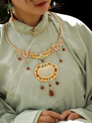 Model wearing a traditional Chinese longevity lock collar necklace with carved jade centerpiece and hanging tassels over a light green Hanfu robe, styled as elegant Chinese jewelry