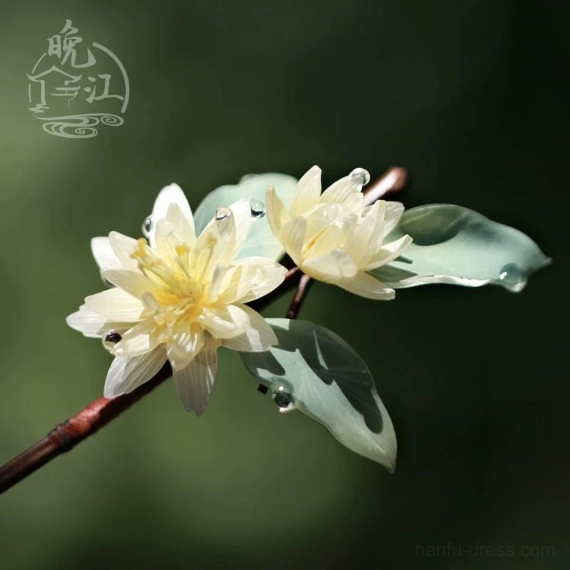 Front close-up of traditional Chinese lotus hair stick featuring two cream lotus blooms sage green leaves clear water drop decorations and dark brown stem