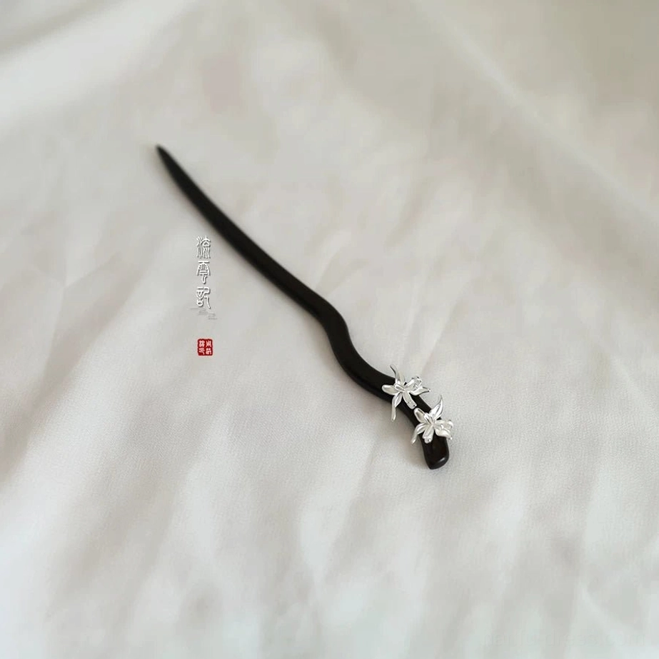 Orchid themed traditional Chinese hair accessory with a curved wooden shaft and silver flower detail on white fabric