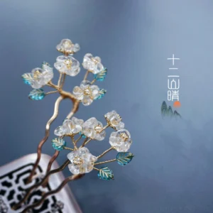 Overhead view of a traditional Chinese pear blossom hairpin with transparent flowers teal leaves and curved gold metal branches