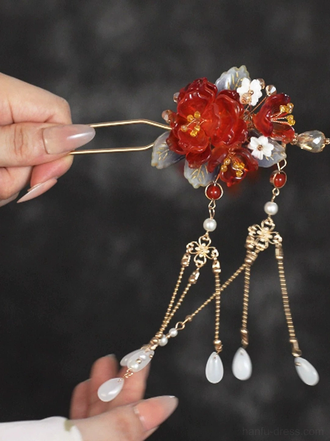 Close-up of a traditional Chinese red peony hair stick showing the double-pronged design decorative beads chain tassels and white teardrop pendants