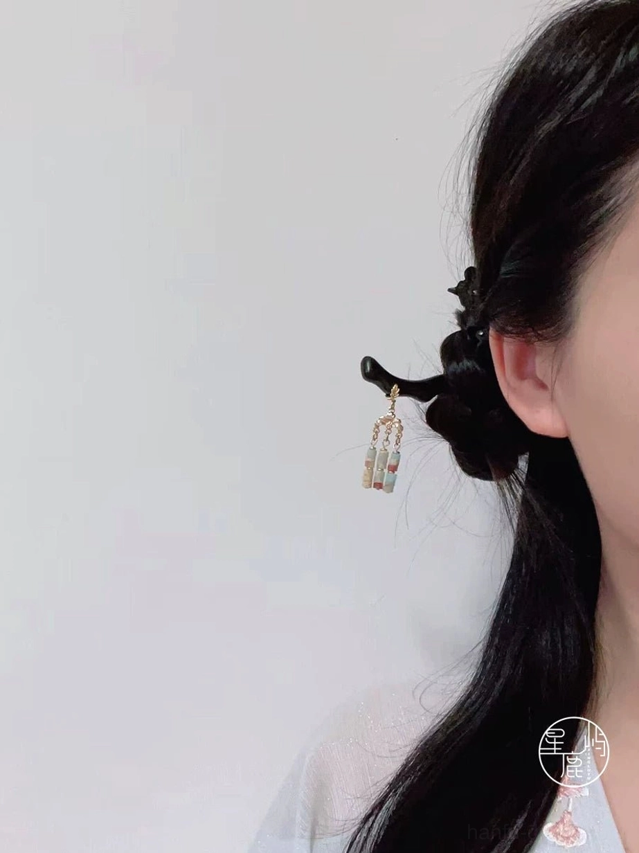 Traditional Chinese tassel hair stick shown in a neat black braided hairstyle, with a curved wooden pin and three decorative stone pendants
