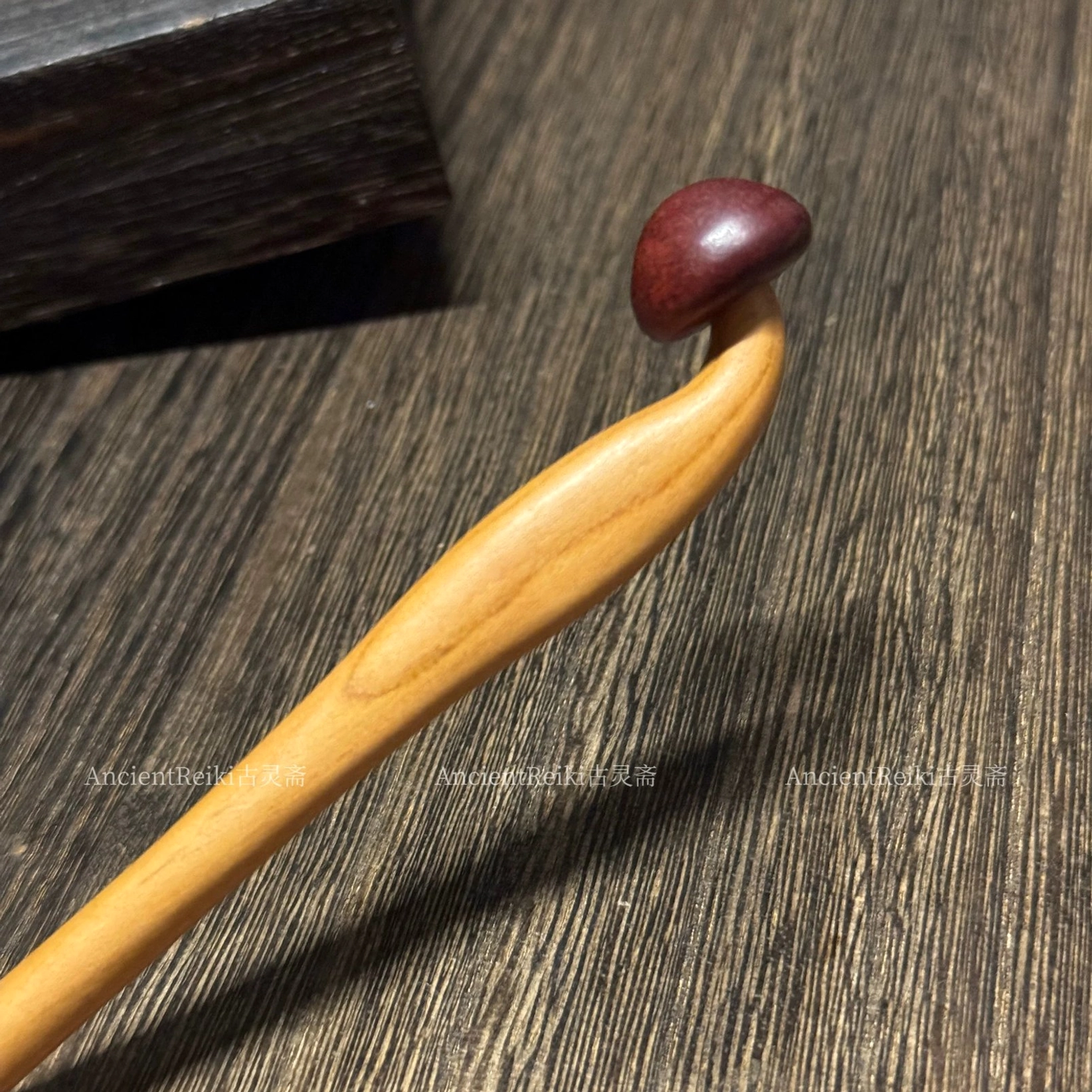 Close-up view of a traditional Chinese wooden mushroom hair stick showing its curved solid wood shaft, two-tone finish, and smooth polished surface