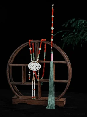 Traditional Chinese yingluo necklace sets displayed on a wooden shelf with red beaded chains, jade accents, carved white jade lock pendants, and long cyan tassels
