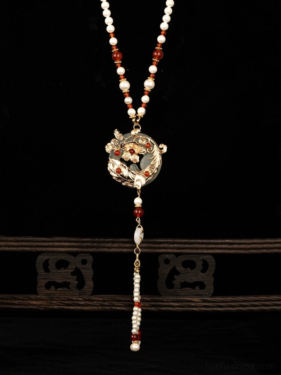 Traditional Chinese yingluo inspired necklace with red agate pearl beads gold pendant and straight beaded tassel on wooden stand