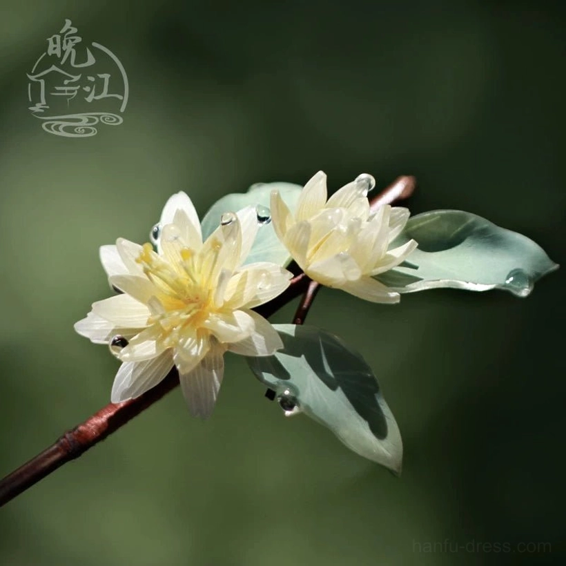 Low-angle close-up of traditional floral Chinese hairpin with pale lotus flowers green leaves clear dewdrop accents and brown wooden stem