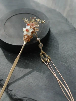 Traditional Hanfu Chinese hair stick with delicate gold flower ornament, long chain tassel, round glass beads, and crystal clusters displayed on a black tray