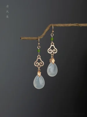 Traditional Hanfu cloud drop earrings displayed on branch showing gold leaf connector green bead and translucent teardrop pendant