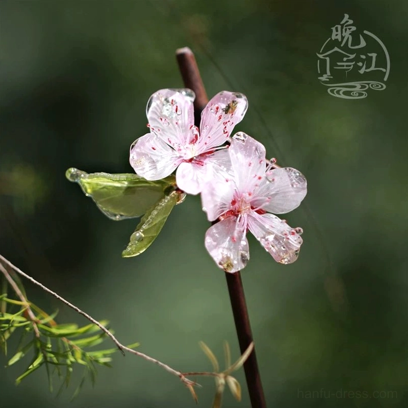 Traditional peach blossom hair stick with two pink translucent flowers on a dark brown wooden-style pin in an outdoor garden setting