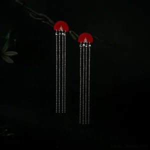 Traditional Chinese fan tassel stud earrings with bright red semicircular tops and shimmering silver chain tassels, photographed on a dark twig for Hanfu and Qipao accessory inspiration