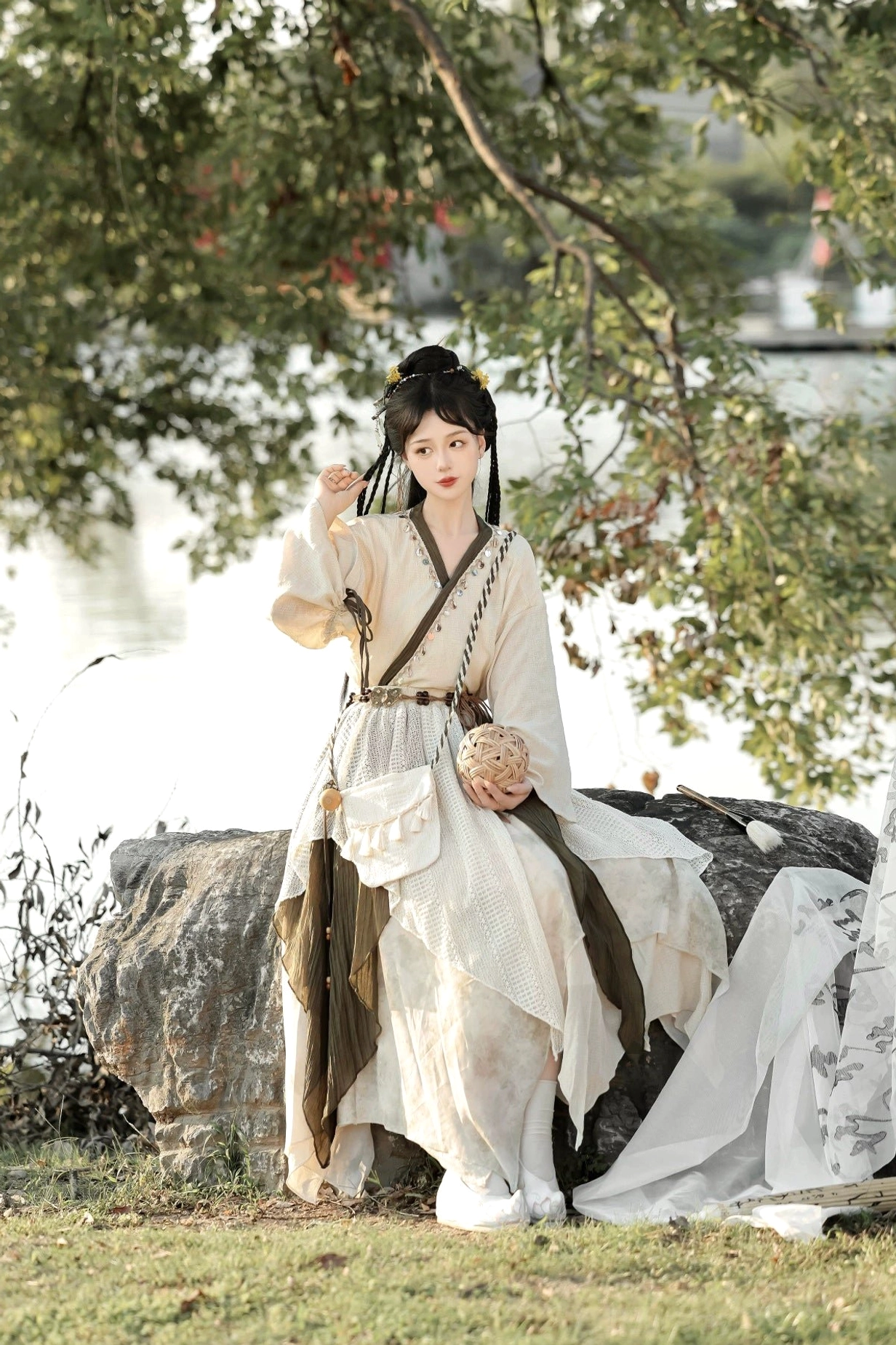 Travelling Lotus Modern Hanfu complete set with beige long sleeve top and relaxed olive green accented asymmetrical skirt in lakeside setting
