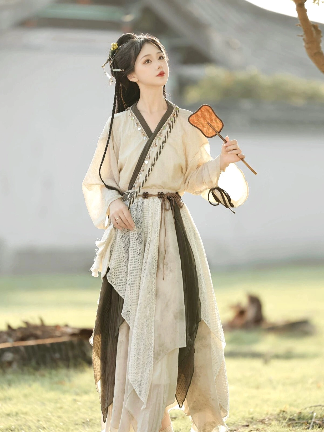 Three-quarter view of Travelling Lotus modern Hanfu outfit with layered asymmetrical skirt, cross V-neck top, and olive green waist accents