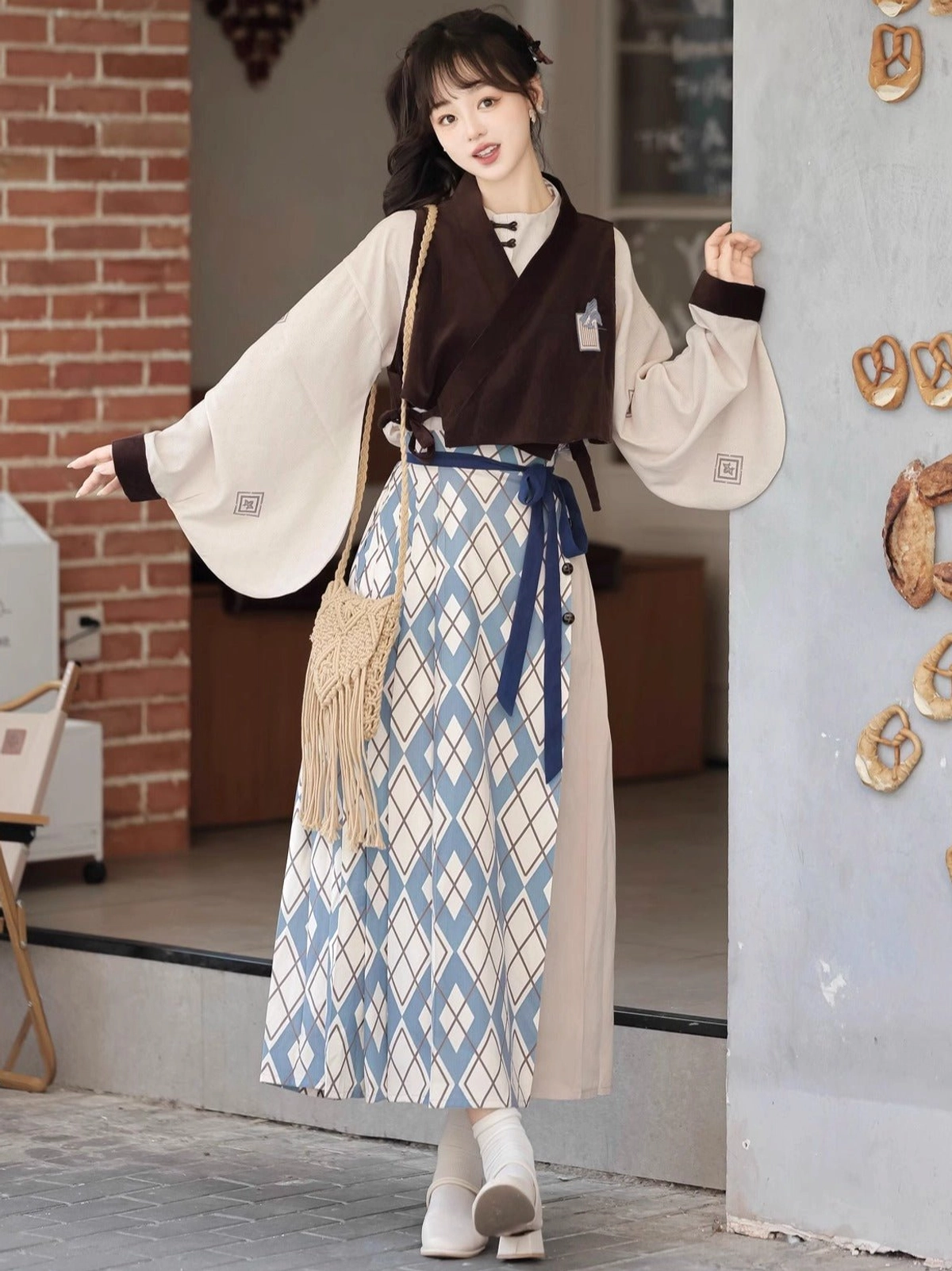 Front three-quarter view of Travels in the Mountains modern Ming Dynasty Hanfu set with beige wide-sleeved top brown embroidered vest and blue mamian skirt