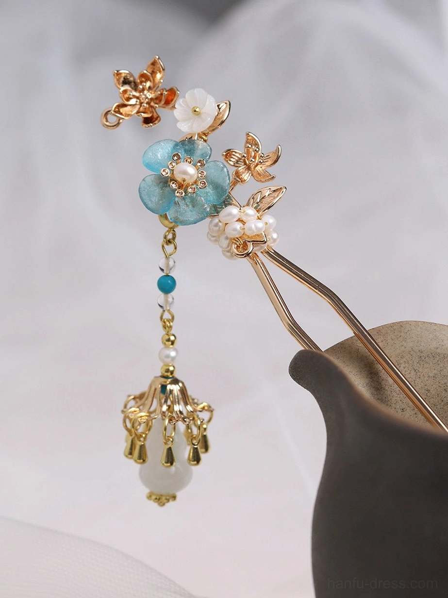 Turquoise blossom Chinese hair stick with white shell flowers pearl clusters gold-tone branches and dangling bead tassel displayed in a dark ceramic vase