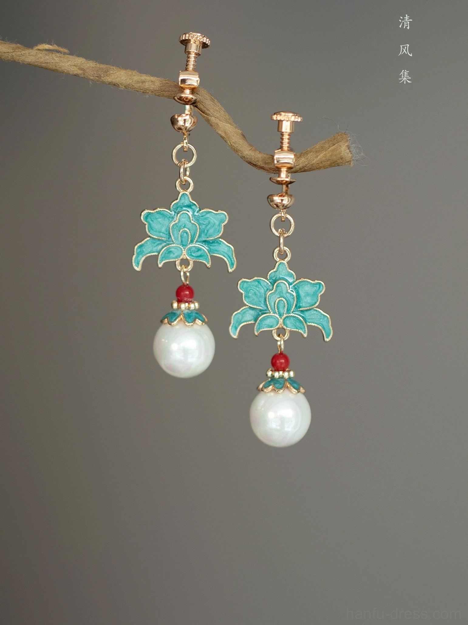Turquoise cloisonne lotus pearl clip-on Chinese earrings with screw-back comfort fittings displayed on a natural twig