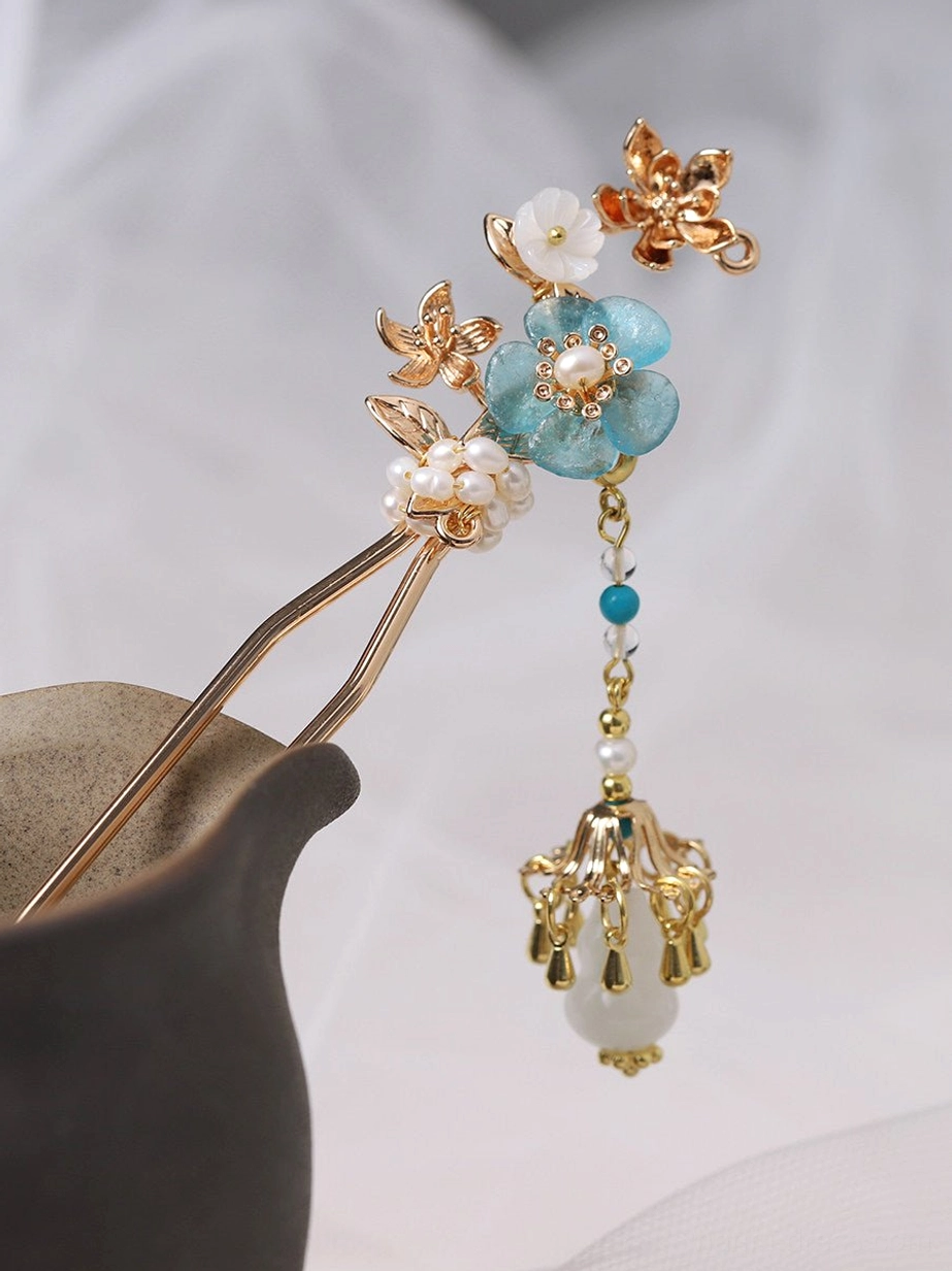 Three-quarter view of turquoise flower Chinese hair stick featuring gold-tone floral branches white shell blossom pearl beads and tassel pendant