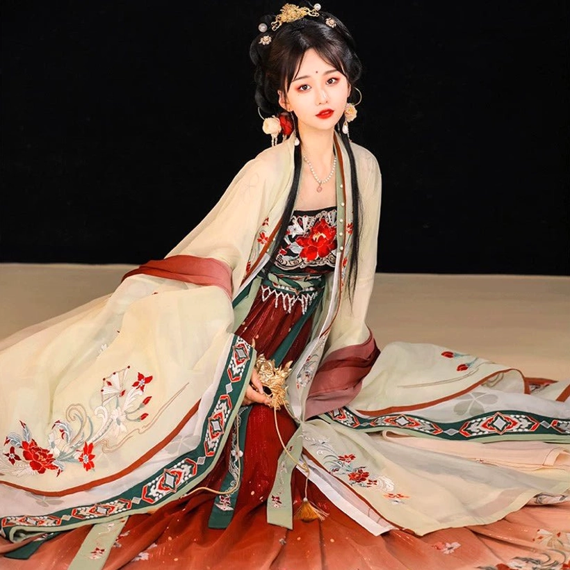Low-angle side view of the Twilight Tang Dynasty Hanfu dress showing its flowing layered skirt, beige and reddish-brown color palette, geometric sleeve trim, and floral embroidery