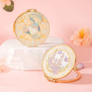 Two-sided Chinese folding pocket mirrors with gold-tone rims, enamel floral designs, and compact vanity mirror construction displayed on a decorative stand