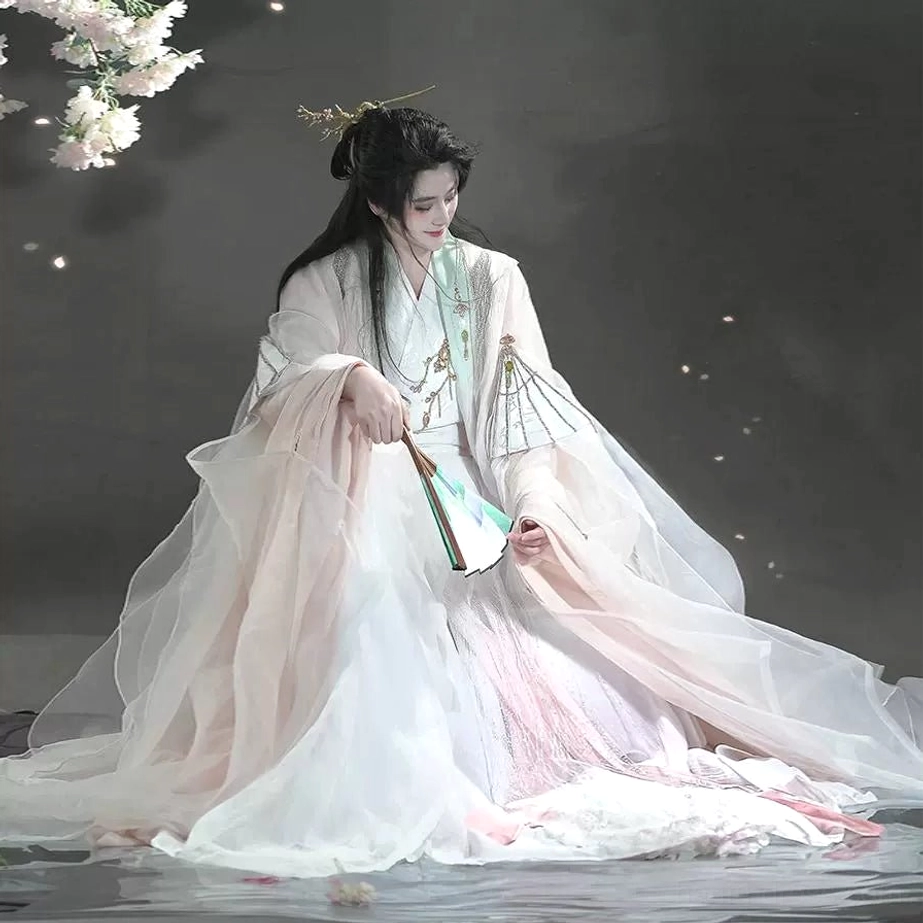 Three quarter front view of unisex flowing Hanfu costume with sheer outer robe soft pink white layers floor length skirt and peach blossom styling