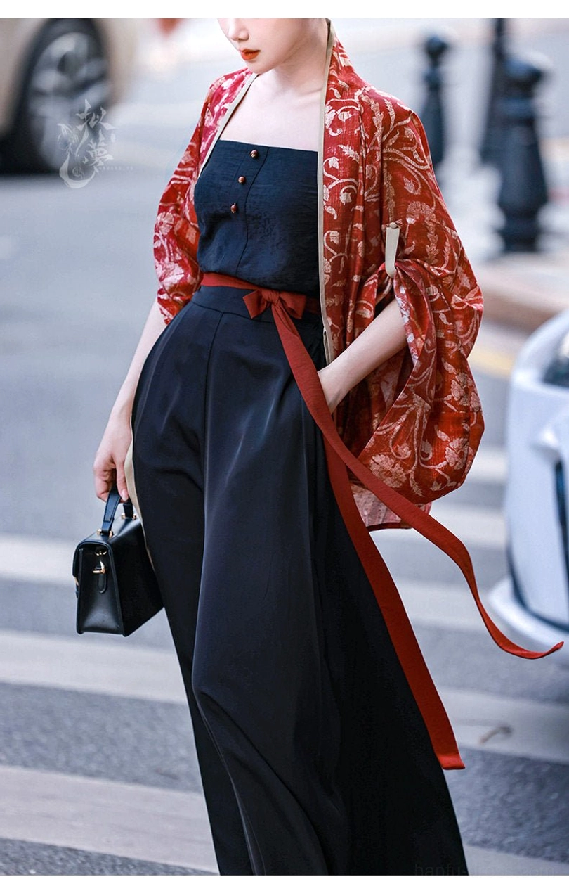 Low-angle front three-quarter view of a Vermilion Bird modern Chinese Hanfu set with red printed cardigan black button camisole and wide-leg trousers