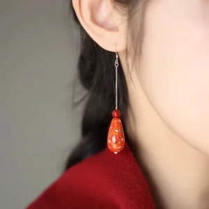 Vermilion lacquer teardrop Chinese hook earring worn on ear with red bead and silver chain detail