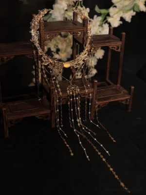 Vintage Chinese bridal back hair crown hair accessory displayed on a wooden stand with circular gold-tone frame, amber-tone bead, and geometric tassel pendants