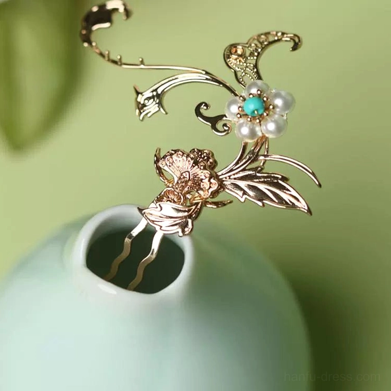 Vintage Chinese floral hair pin with gold-toned carved metalwork, imitation pearl, and turquoise bead accents displayed on a large light cyan porcelain vase