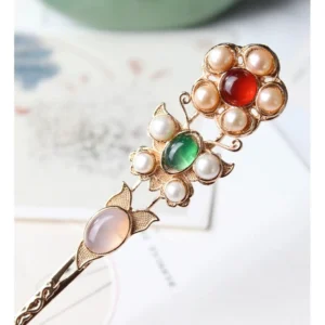 Vintage Chinese floral hairpin with gold toned filigree, red agate, green chalcedony, freshwater pearls, pink jade and butterfly details displayed on ink painting paper