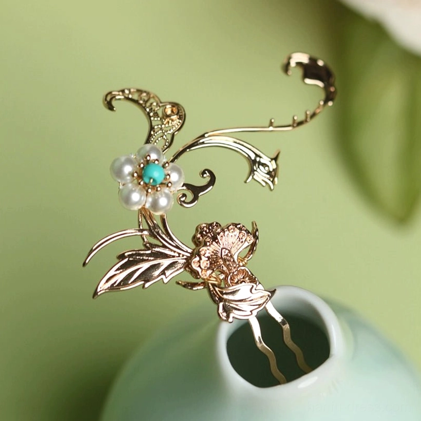 Close-up side view of a vintage Chinese hair pin with intricate hollow floral metalwork, imitation pearl, and turquoise bead details resting on a light cyan porcelain vase