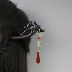 Close-up of a vintage Chinese hair stick with black carved body, red and gold tassel, and traditional updo styling